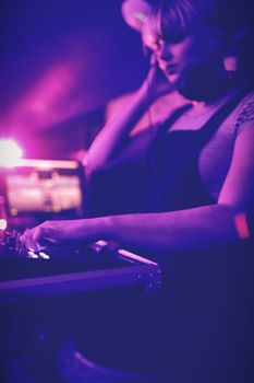 Female dj listening to headphones while playing music in bar