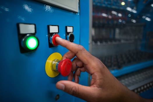 Hand pressing a red button in a electric room