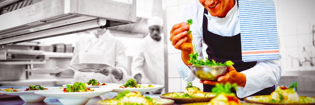 Happy chef garnishing appetizer plates at order station in restaurant