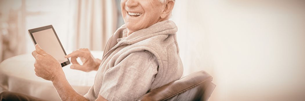 Portrait of senior man using digital tablet while sitting at home