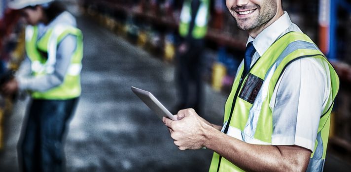 Worker in warehouse looking at camera with yellow safety vest