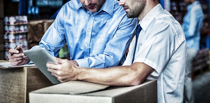 Portrait of managers are working with a tablet in the middle of cardboard boxes in a warehouse