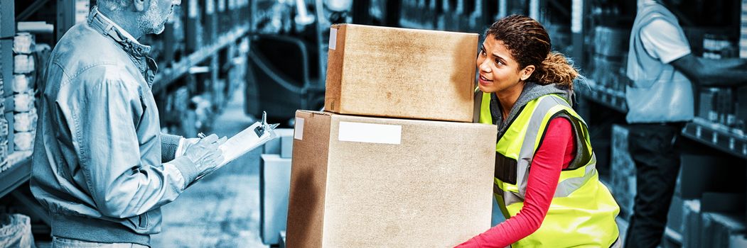 Worker holding cardboard boxes looking her manager in a warehouse