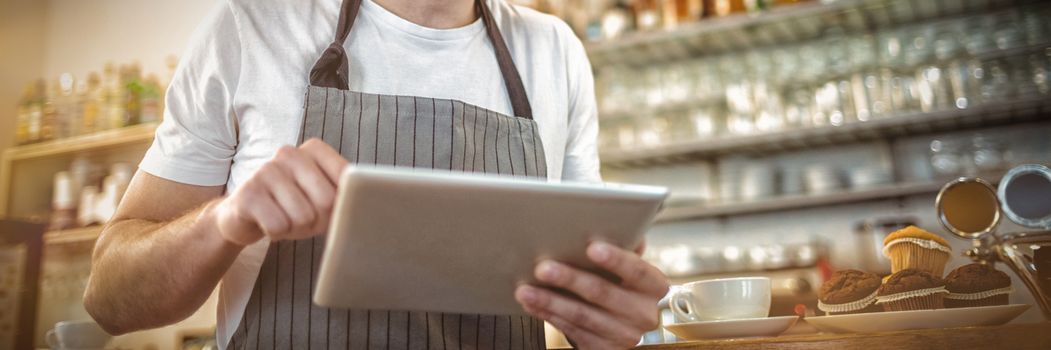 Happy male barista using digital tablet at cafe