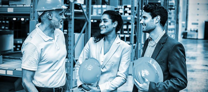 Happy warehouse managers and worker standing together in warehouse office