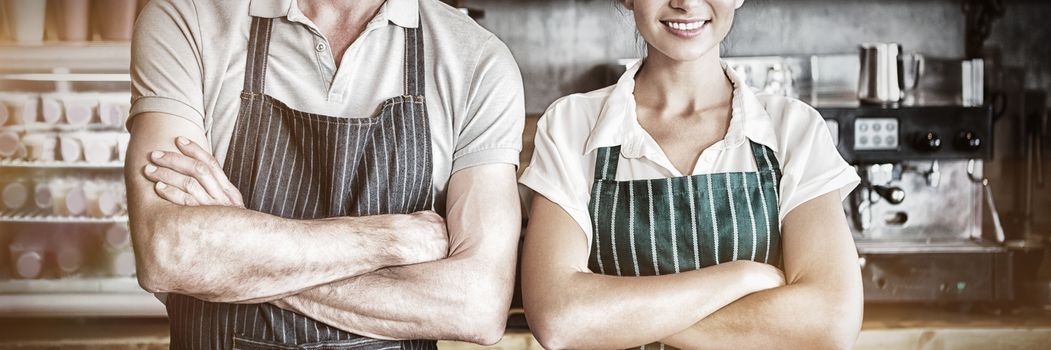 Portrait of waiter and waitress with arms crossed in cafeteria