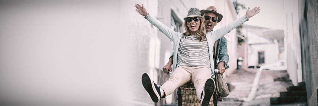 Mature couple enjoying while riding bicycle on street