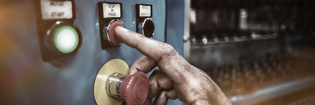 Hands of factory worker pressing a red button on the control board in factory