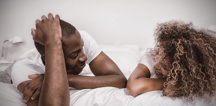 Young couple lying on bed and talking in bedroom