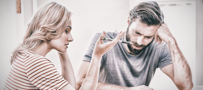 Worried young couple checking on bills at home