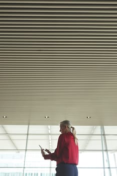 Low angle view of senior Caucasian businesswoman using digital tablet in modern office building