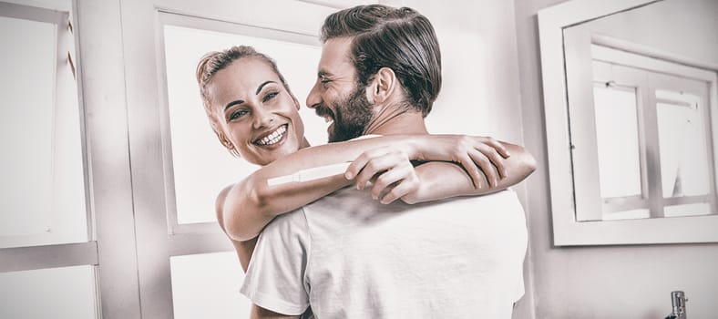 Woman holding pregnancy test while embracing man at home