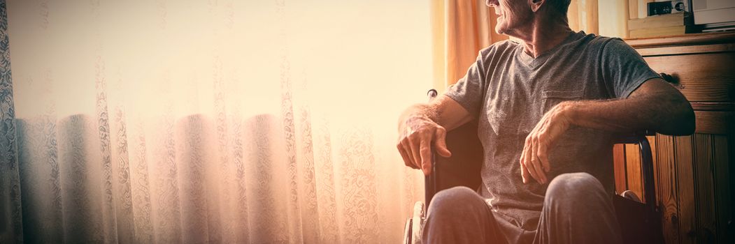 Thoughtful senior man looking away while sitting on wheelchair in nursing home