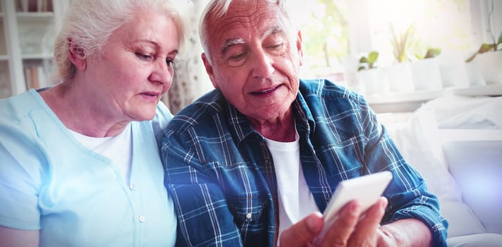 Senior couple using mobile phone at home