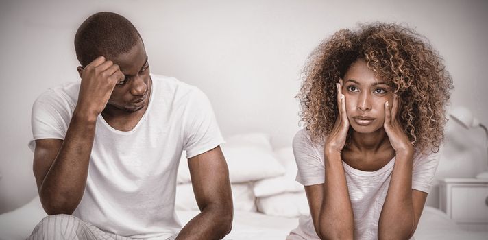 Upset couple ignoring each other after fight on bed in bedroom