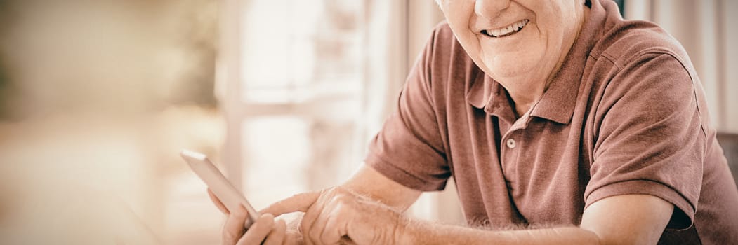 Portrait of smiling senior man using mobile phone at home