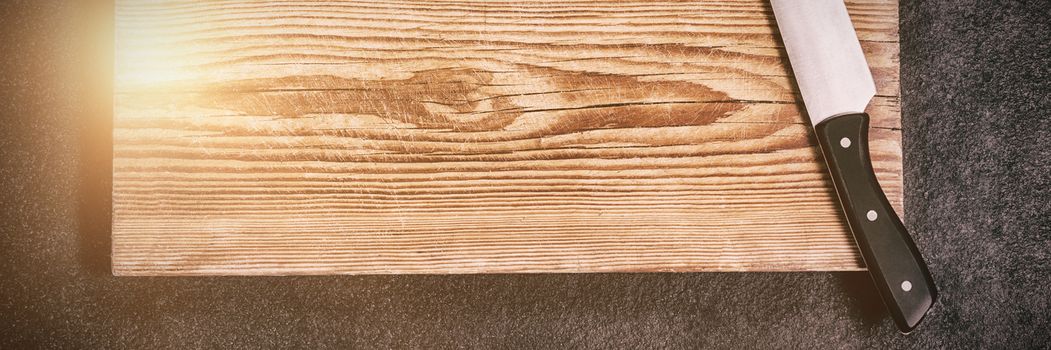 Knife on wooden board against black background