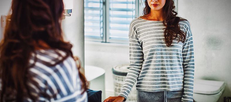 Woman looking at herself in the bathroom mirror at home