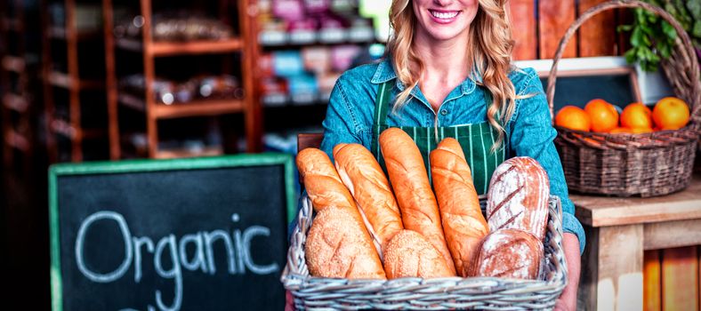 Smiling woman holding a basket of baguettes in organic shop of supermarket