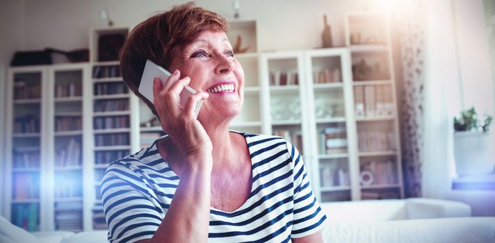 Senior woman talking on mobile phone in living room at home