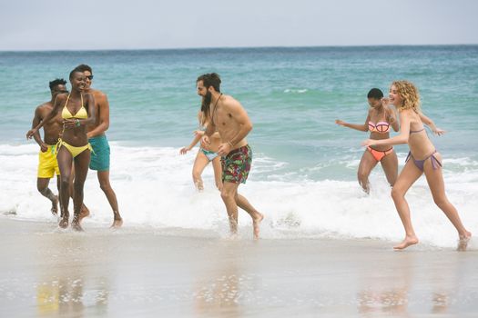 Front view of multi ethnic group of friends enjoying and having fun on water at beach on sunny day