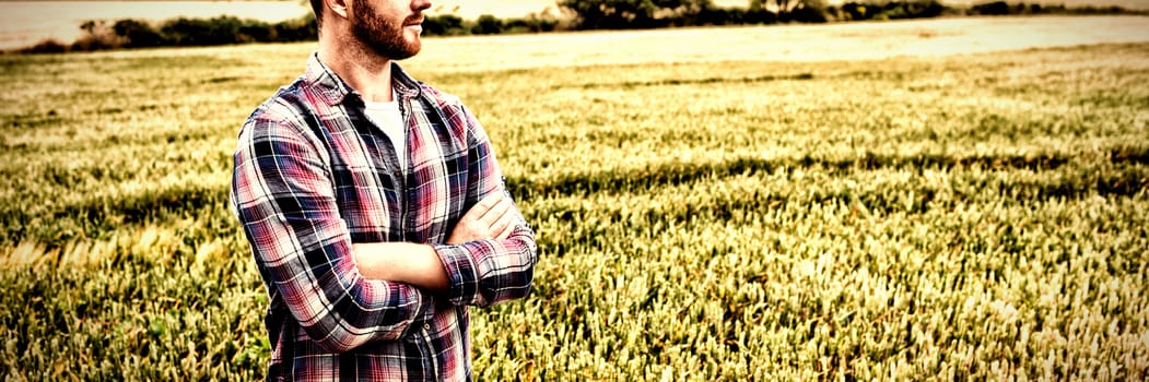 Farmer standing with arms crossed while looking away in field