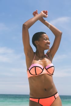 Front view of beautiful African-american woman posing while standing on beach on a sunny day