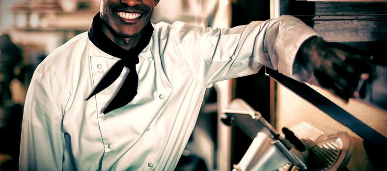 Portrait of smiling head chef standing in commercial kitchen
