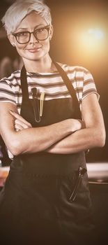 Portrait of female hairdresser standing with arm crossed at a salon