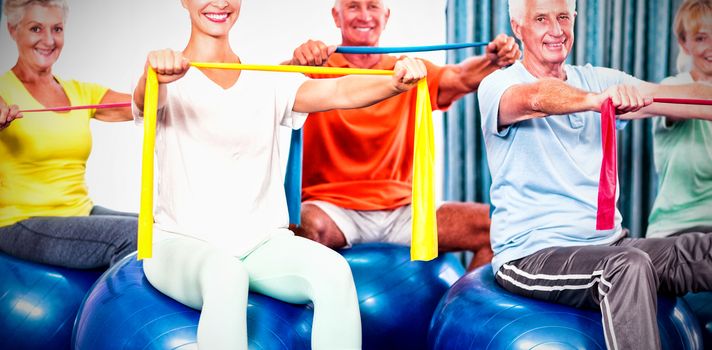 Portrait of seniors using exercise ball and stretching bands during sports class