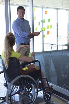 Disabled female and male executive discussing over sticky notes in the office