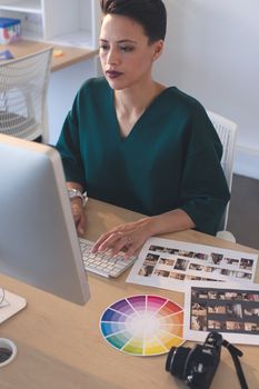 Female graphic designer working on computer at desk in the office