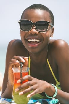 Close up of African-american woman lying at beach while having pineapple  