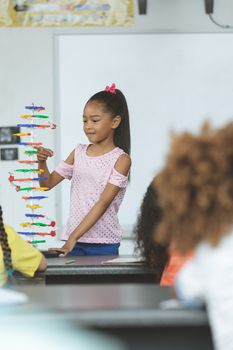 Front view of a mixed-race ethnicity schoolgirl analyzing DNA structure model in classroom at school