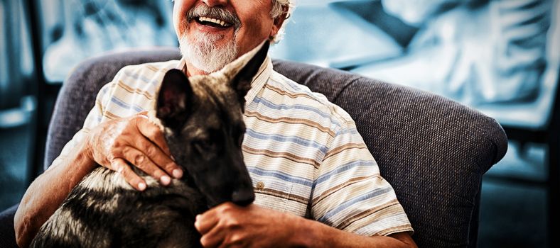 Portrait of smiling senior man sitting with puppy on chair at retirement home