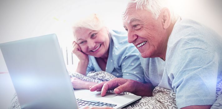 Senior couple using laptop in bedroom at home