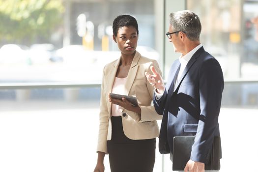 Front view of African American businesswoman and Caucasian businessman interacting with each other in lobby at office lobby