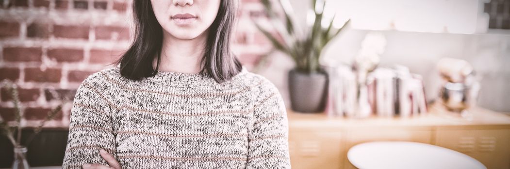 Portrait of confident beautiful young woman standing with arms crossed at coffee shop