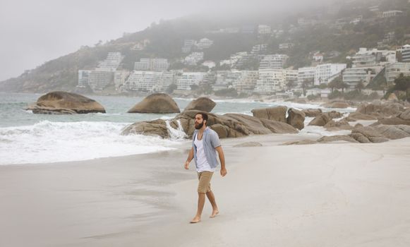 Front view of mixed race man walking at the beach on a sunny day