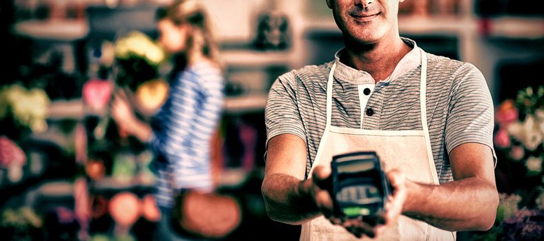 Portrait of florist showing credit card terminal in flower shop