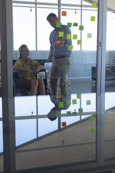 Disabled female and male executive discussing over sticky notes in the office