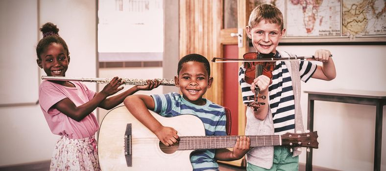 Portrait of smiling children playing musical instruments in classroom at school