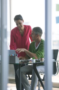 Front view of attentive business people discussing over laptop at desk in office