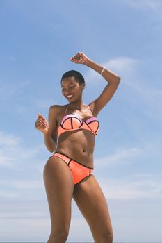 Low angle view of African american woman posing while standing on beach on a sunny day