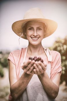 Portrait of smiling female farmer holding red grapes at vineyard