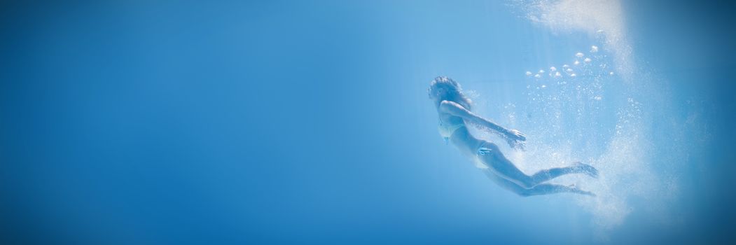 Fit woman swimming under water in the pool