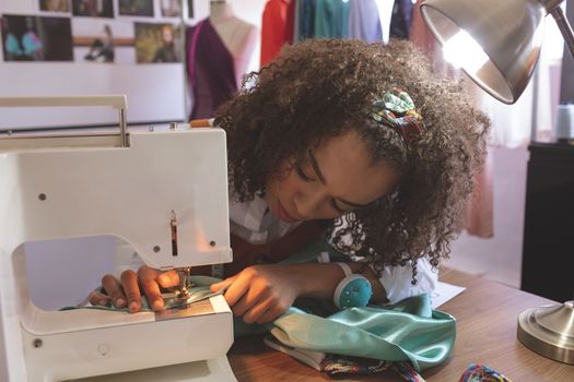 Front view of female fashion designer working with sewing machine