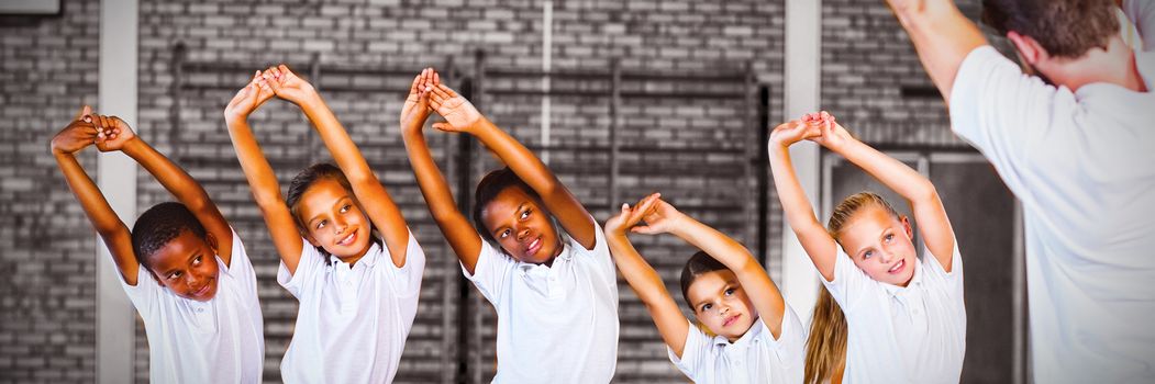 Teacher teaching exercise to school kids in basketball court at school gym