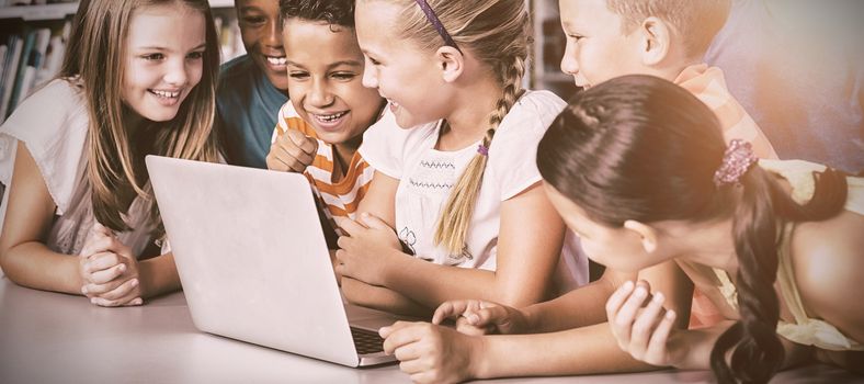School kids using laptop in library at school