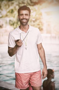 Portrait of male instructor standing at poolside